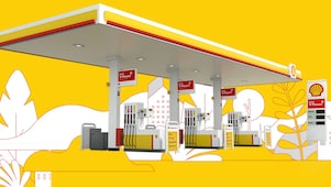 Illustrated Shell service station set within a stylised landscape featuring trees, buildings and rolling hills in Shell brand colours of yellow, red and white.