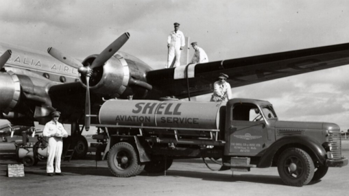 Shell Aviation Service tanker refuelling a Trans Australia Airlines Douglas DC‑6B aircraft, with crew members assisting.