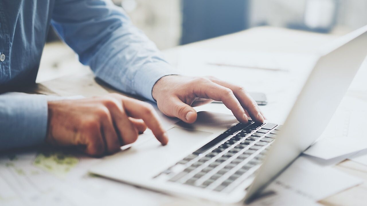 Laptop, mobile phone and paperwork on work desk.