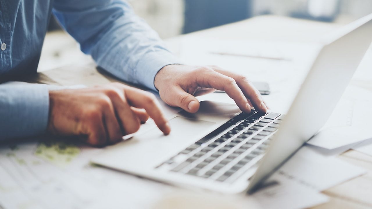 Laptop, mobile phone and paperwork on work desk.
