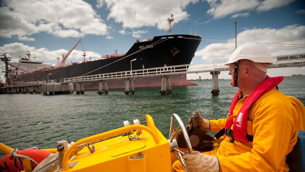 Jetty worker manning response vessel next to tanker