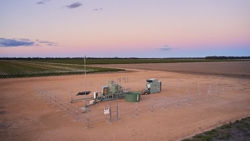 An aerial view of a Shell QGC gas well site at sunset.