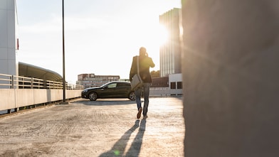 Mature man walking on parking level to his car, talking at the phone