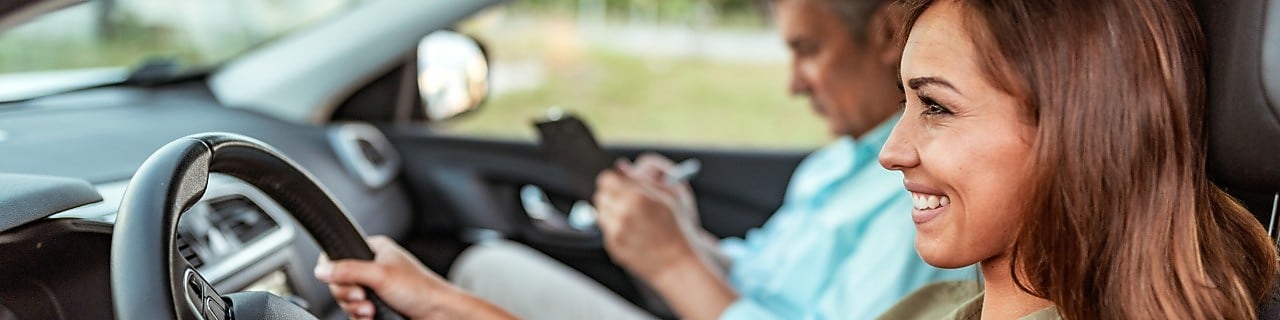 A woman in the car with a professional driving instructor.