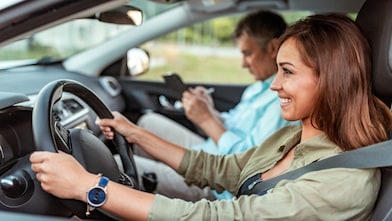 A woman in the car with a professional driving instructor.