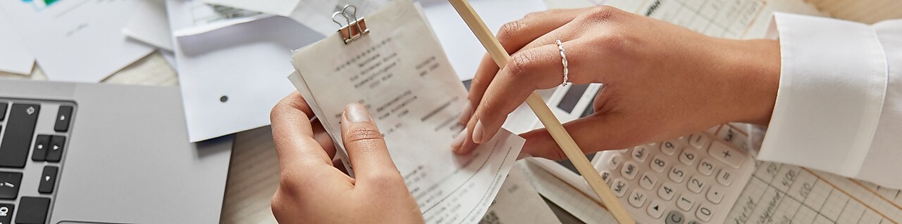 hands holding receipts with paper in the background