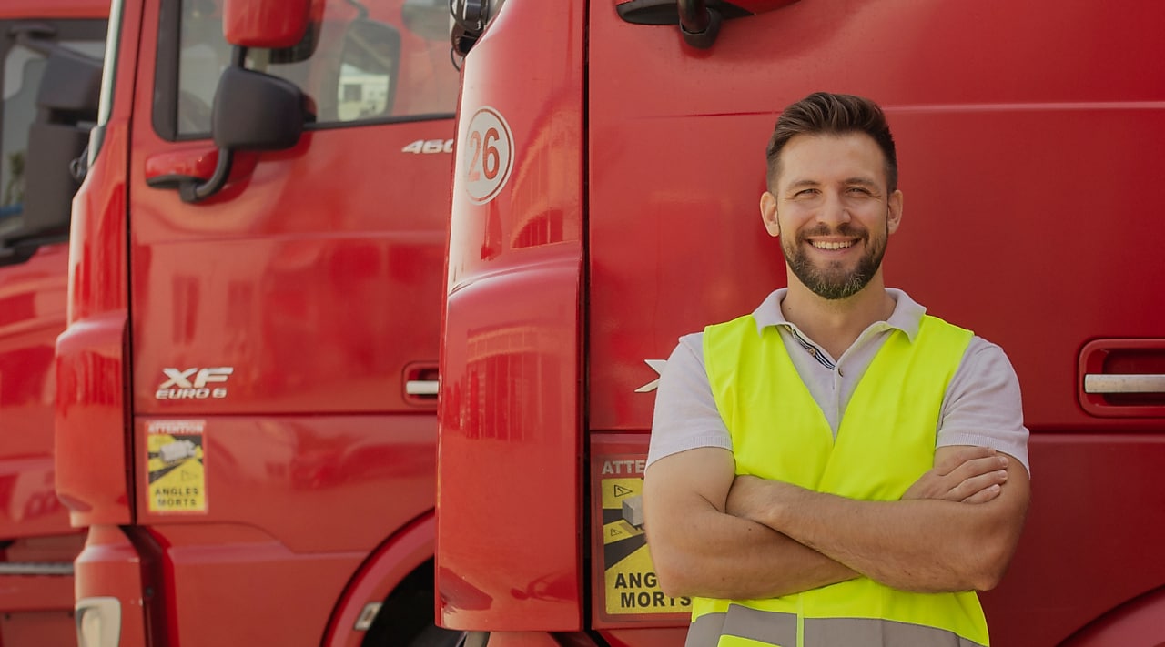 A man stands confidently in front of a lineup of red trucks, showcasing their vibrant color and sturdy design.