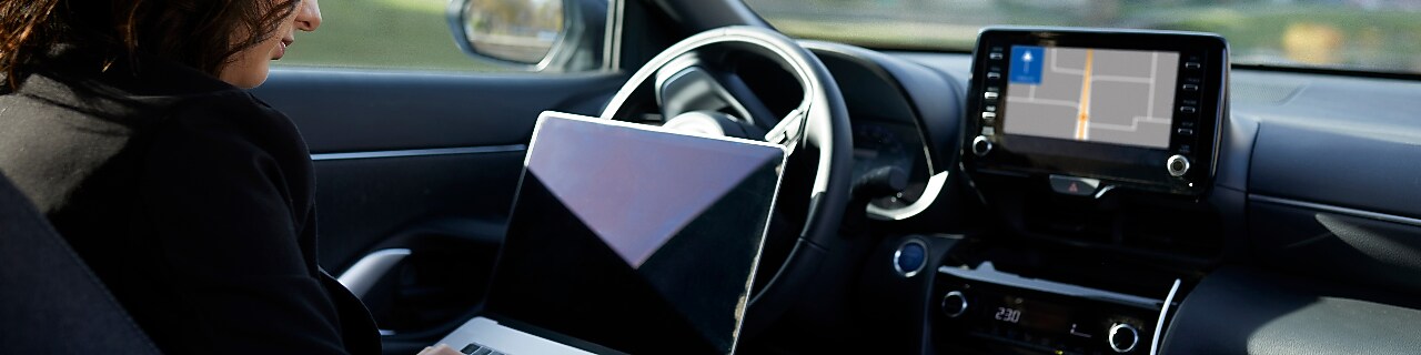 Businesswoman with laptop working in driverless car