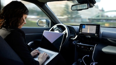 Businesswoman with laptop working in driverless car