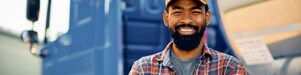 Happy African American truck driver with crossed arms looking at camera.