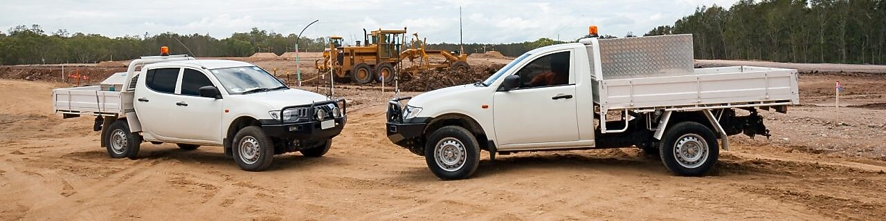 Two white utes on a work site