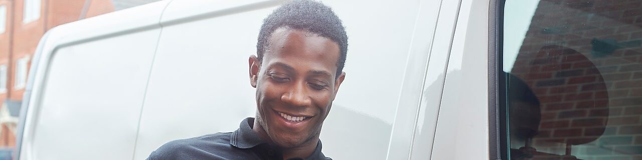 Man on his phone and tablet outside his van