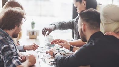 A team of colleagues sit around a table completing an activity.