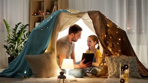 A father and a daughter looking at a tablet in a tent