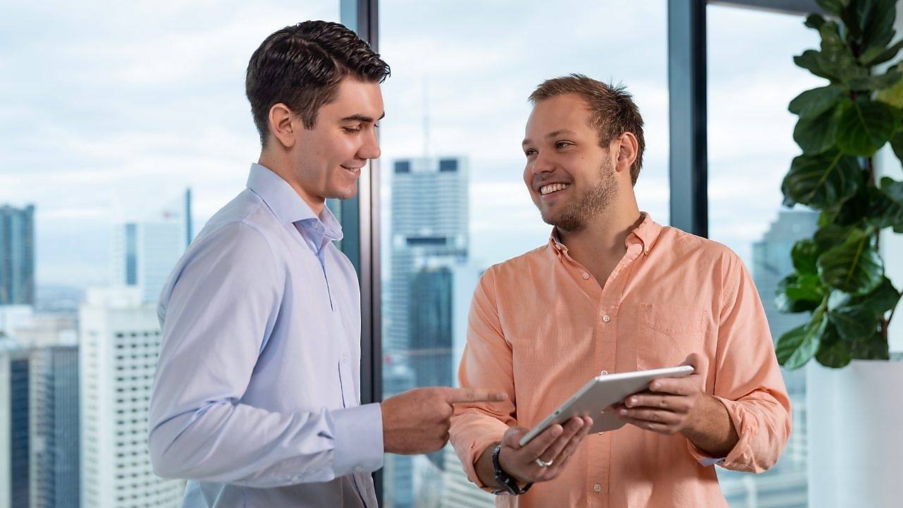A couple of employees in an office discussing with a tablet