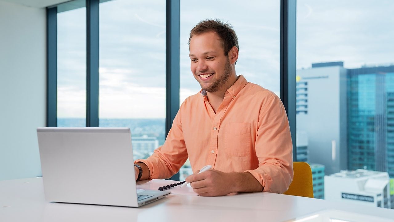 An individual seated at a desk, using a laptop for work