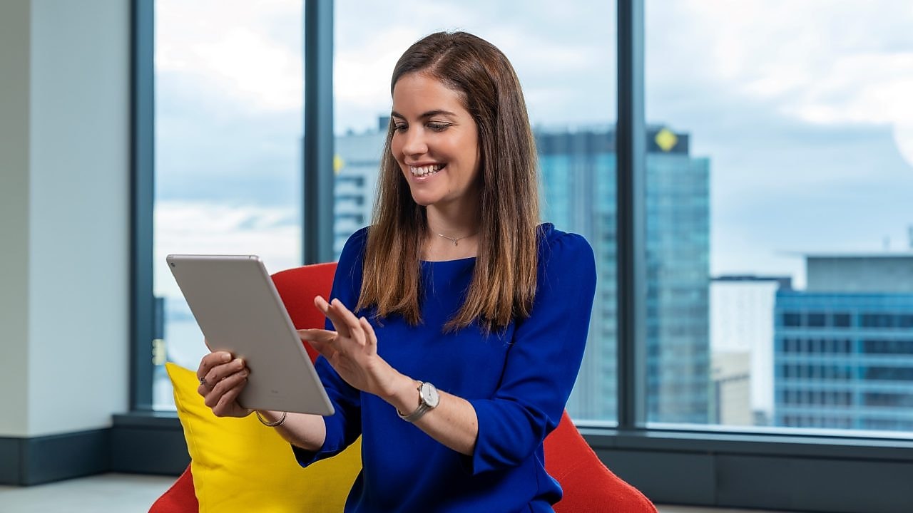An individual sitting in an office chair, utilizing a tablet
