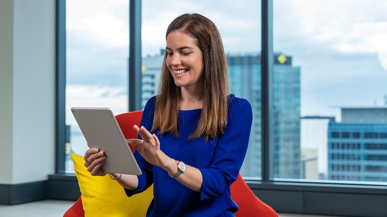 An individual sitting in an office chair, utilizing a tablet