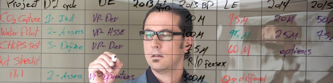 employee writing on transparent board.