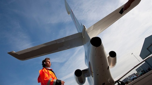 bottom up view of staff walking behind the tail end of a plane
