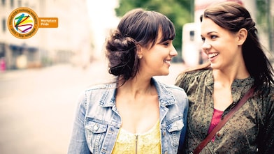 Two girls smile at each other as they walk down the street
