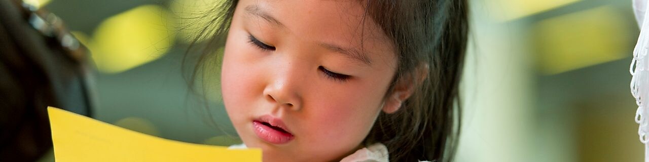 Young girl cutting paper with scissors.