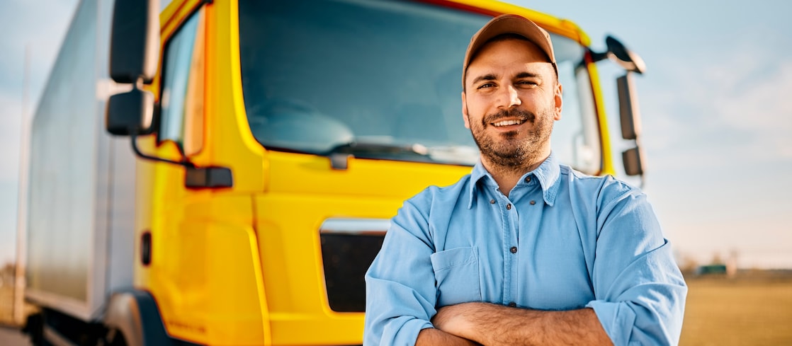 Happy man standing in front of his truck