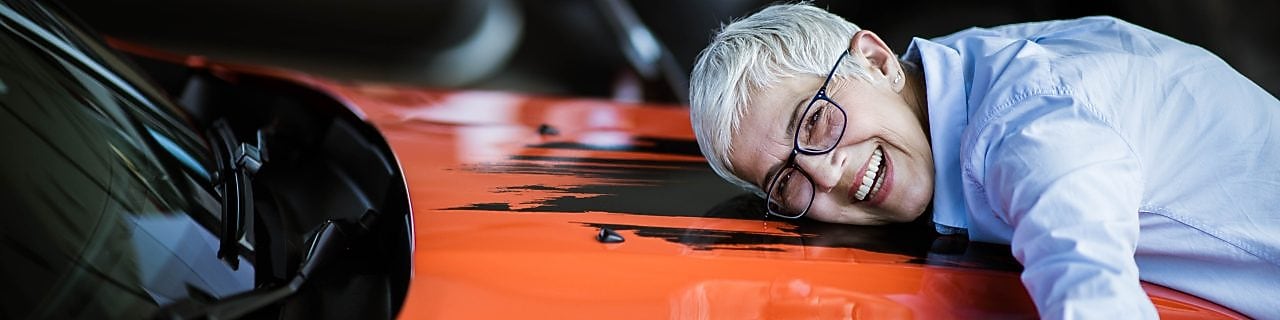 A woman hugs the bonnet of her red car