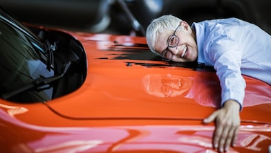 A woman hugs the bonnet of her red car