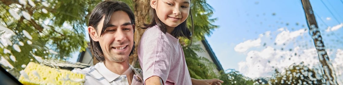 Father and daughter cleaning the car