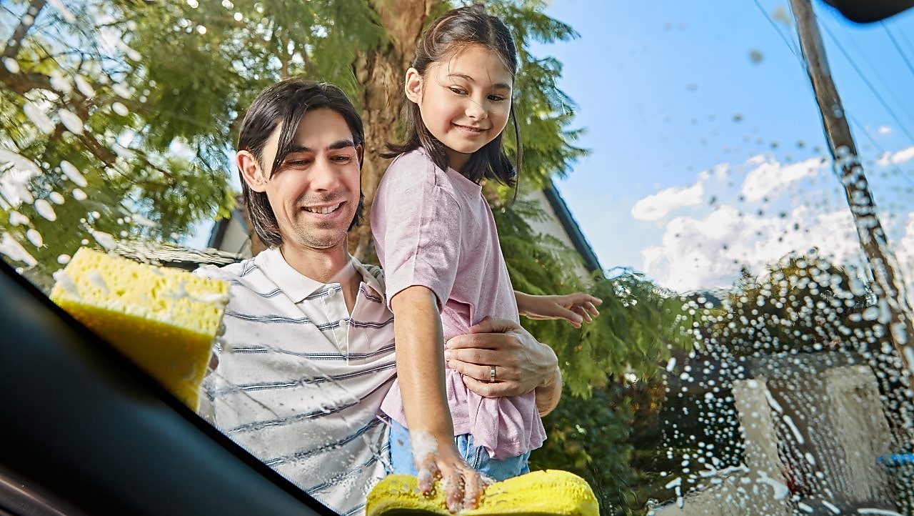 Father and daughter cleaning the car
