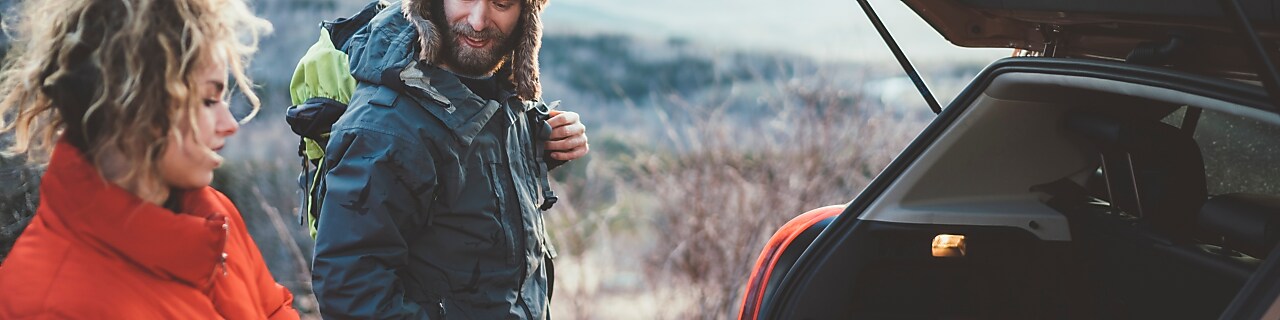 Couple on hiking taking backpacks from the car trunk