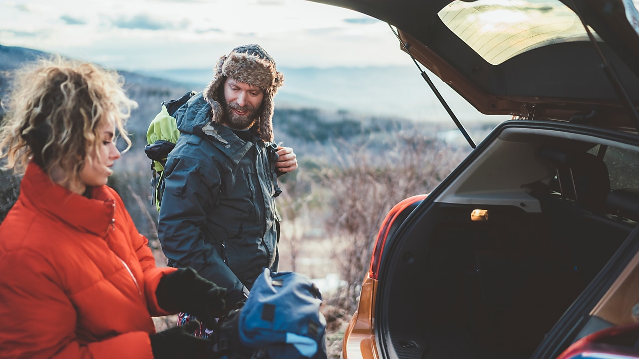 Couple on hiking taking backpacks from the car trunk