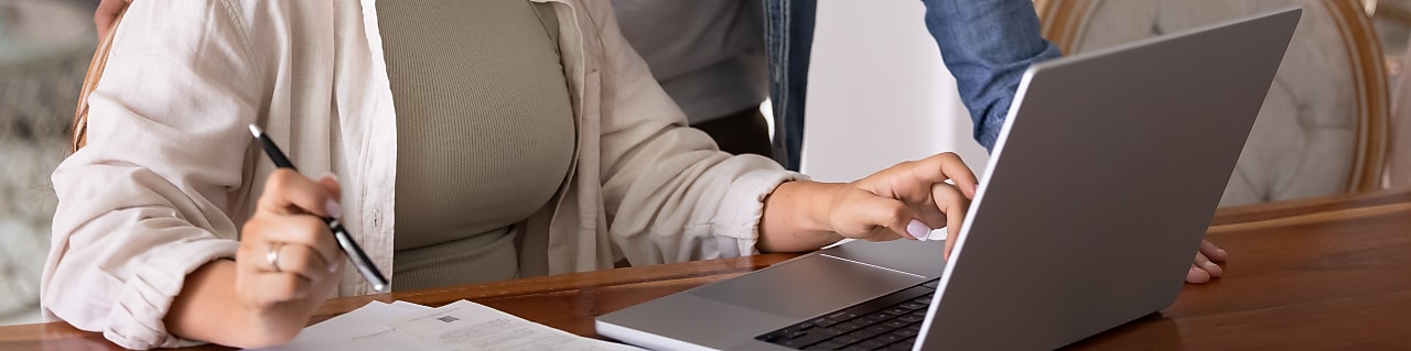 Woman sitting at desk looking at laptop with man looking over her shoulder