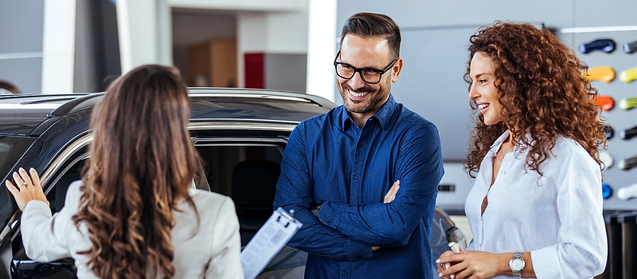 Couple chatting with car sales assistant