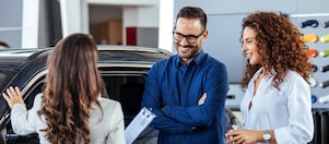 Couple chatting with car sales assistant