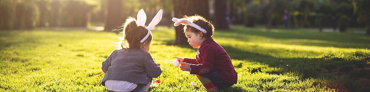 two children squatting in the park wearing bunny ears