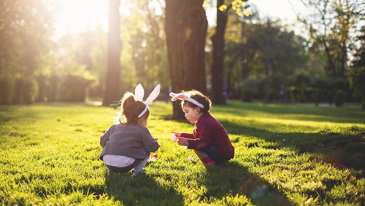 two children squatting in the park wearing bunny ears