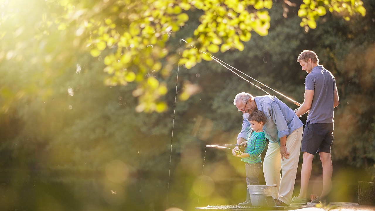 Grandpa, son and grandson fishing  by the lake
