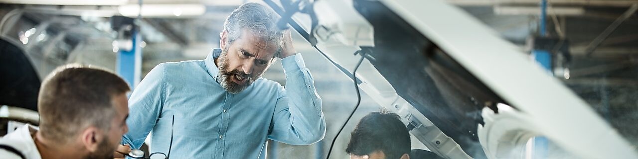 Group of men looking at a broken down car