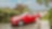A large, cream-coloured dog sits in a driveway in front of a red car.