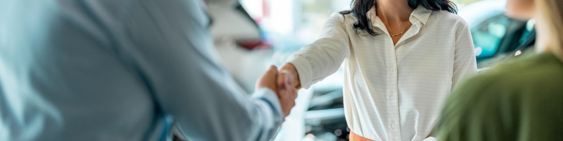 Business woman shaking hands with a male after a car loan agreement was signed.