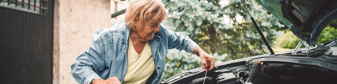 VA woman checks the oil dipstick in a car engine