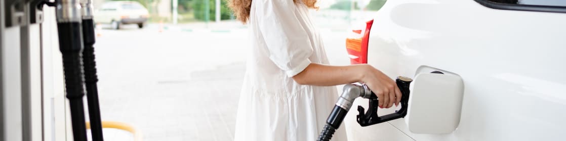 Young woman refuelling car at gas station