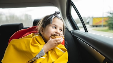 A child eating a donut and smiling inside a car