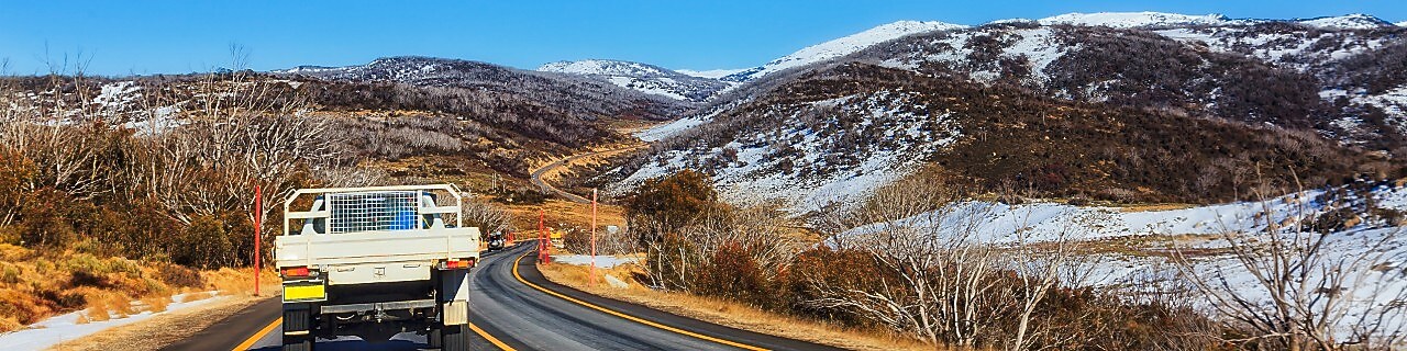 A ute drives through the snowy mountains region of Australia.
