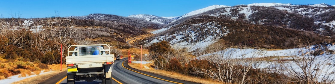 A ute drives through the snowy mountains region of Australia.