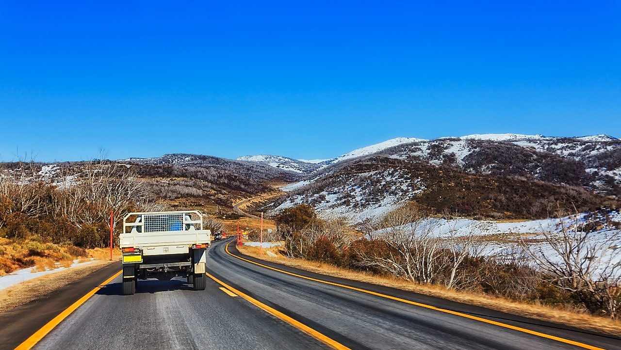 A ute drives through the snowy mountains region of Australia.