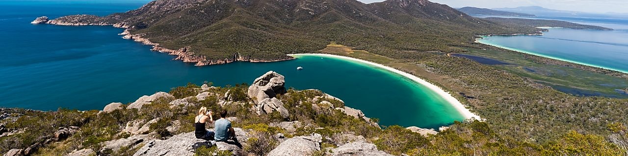 A couple take in the view of Wineglass Bay from a lookout in Freycinet National Park