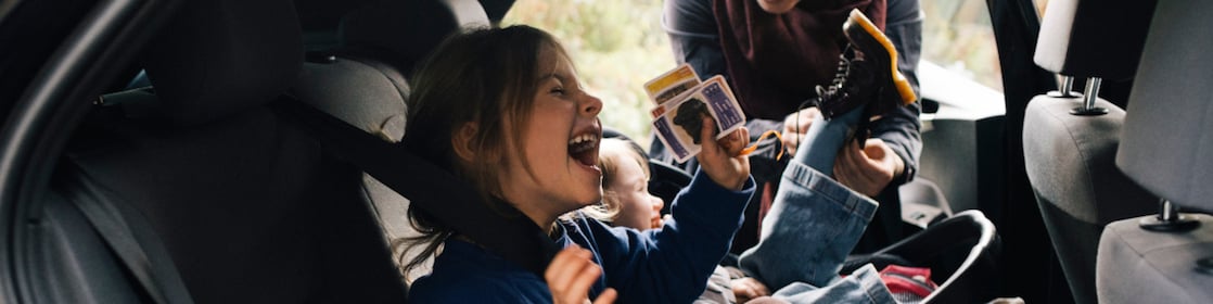 little girl laughing in the back of the car with mother in the background
